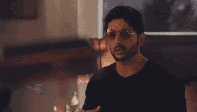 a man wearing sunglasses is sitting in front of a window in a room .