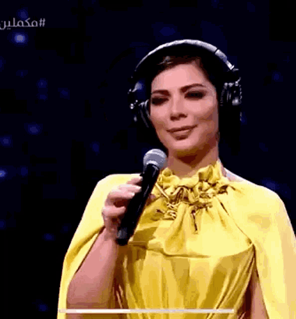 a woman in a yellow dress is holding a microphone and wearing headphones