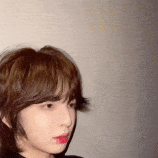 a woman with short hair and red lipstick is standing in front of a wall .
