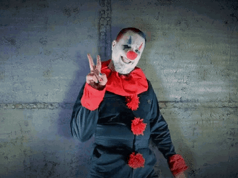 a man dressed as a clown giving the peace sign