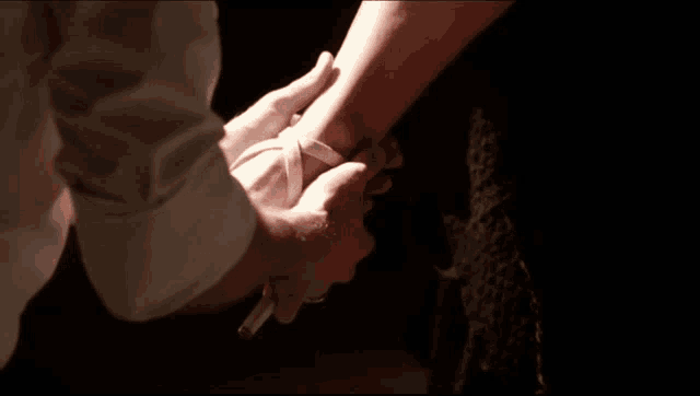 a man is holding a woman 's wrist with a white ribbon