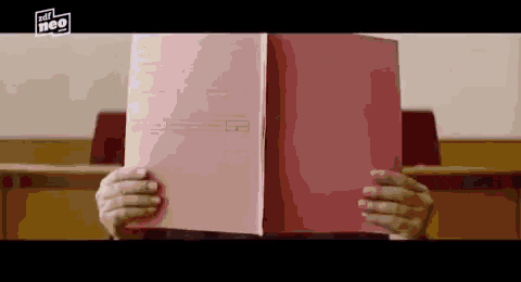 a person is holding a pink folder in front of their face and the word neo is on the bottom