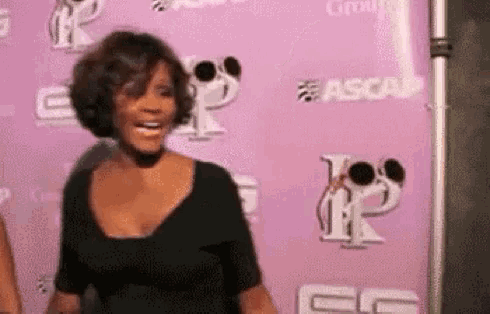 a woman is standing in front of a pink wall with a sign that says ascap .