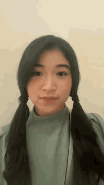 a young woman with pigtails is wearing a green shirt and headphones .