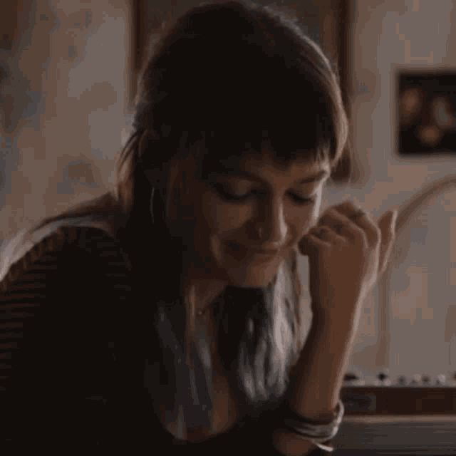 a woman with blue hair is sitting at a table with her hand on her chin .