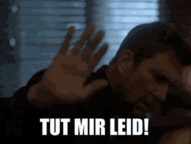 a man is making a stop gesture with the words tut mir leid below him