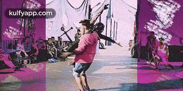 a man in a pink shirt is riding a skateboard in front of a crowd of people .