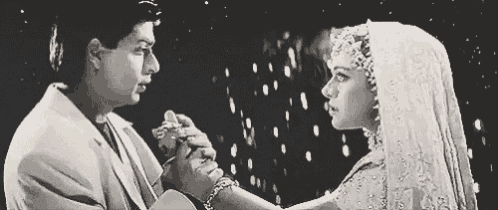a black and white photo of a man and a woman holding hands in the rain .