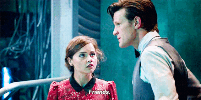 a man and a woman are standing next to each other and the man is talking to the woman and says `` friends '' .