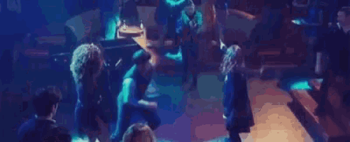 a group of people are dancing in a dark room with a lot of lights .