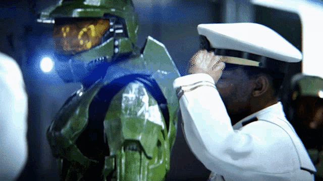 a man in a white hat salutes another man in a green suit