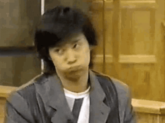 the man is wearing a suit and tie and making a funny face .