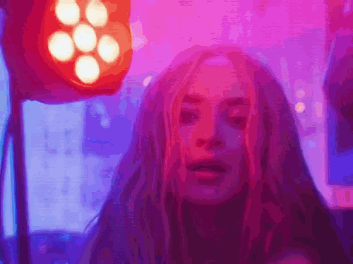 a close up of a woman 's face with purple and red lights in the background