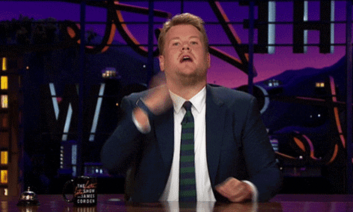 a man in a suit and tie is sitting at a table with a cup that says the late show with james corden