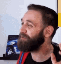 a man with a beard is making a funny face while standing in front of a wall .