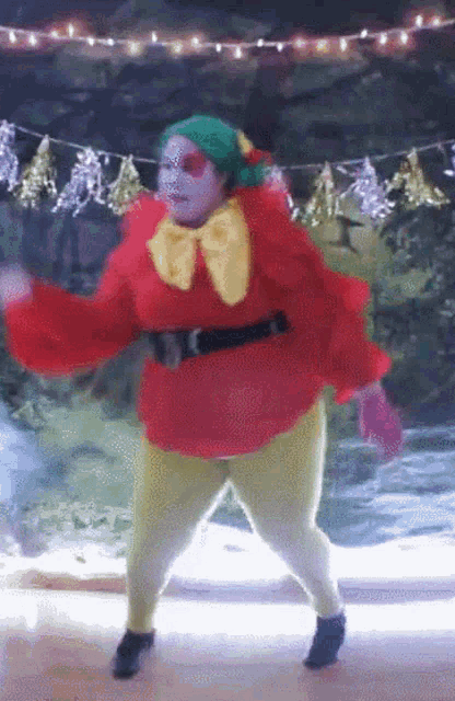 a woman in a clown costume is dancing in front of christmas lights