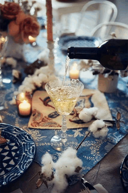 a bottle of wine is being poured into a martini glass on a table