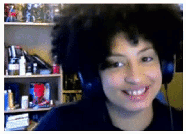 a person wearing headphones is smiling in front of a bookshelf