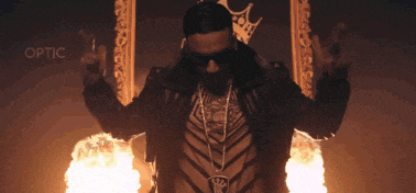 a man with a crown on his chest is standing in front of flames and the word optic is above him