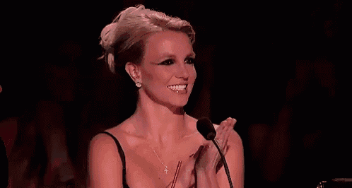 a woman is applauding in front of a microphone while smiling .
