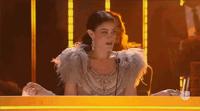 a woman in a feathered dress is sitting at a table