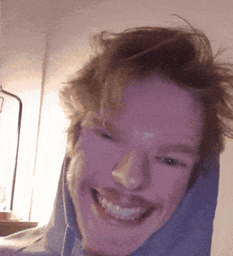 a man with a beard wearing a blue hoodie smiles for the camera