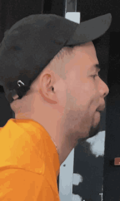 a man wearing an orange shirt and a black hat with the letter n on it