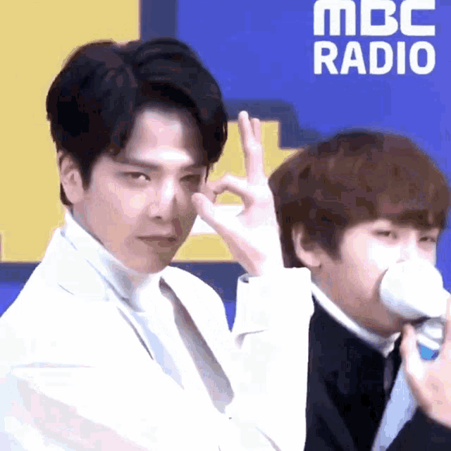a man in a white suit giving the ok sign
