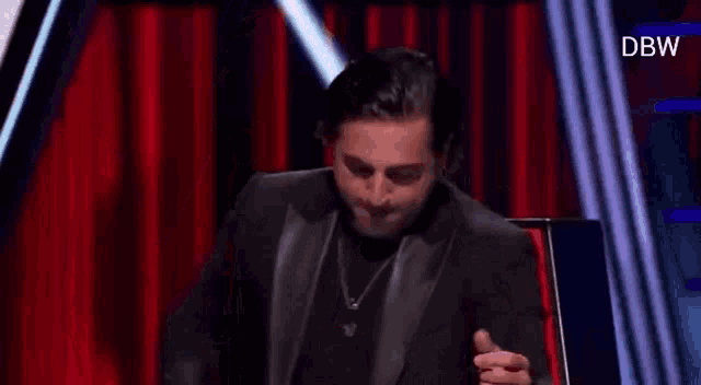 a man in a suit is sitting in a chair on a stage .