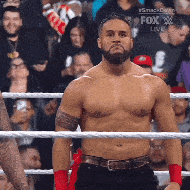 a shirtless wrestler is standing in a ring with a fox live advertisement behind him