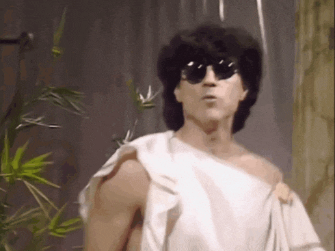 a shirtless man wearing sunglasses and a towel around his shoulder