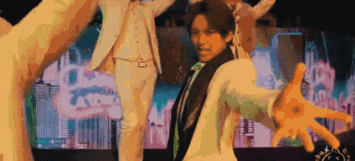 a man in a white suit and tie is dancing on a stage .