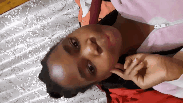 a woman is laying on a bed with her hand on her chin