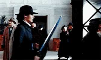 a man in a hat is holding a sword in front of a crowd of people