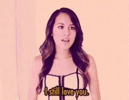 a woman says i still love you while standing in front of a yellow wall