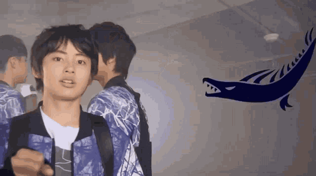 a group of young men are standing next to each other in a dark room with a shark flying in the background .