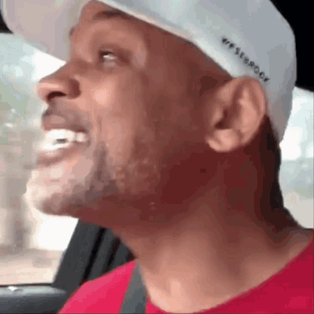 a man wearing a red shirt and a white hat that says we strong