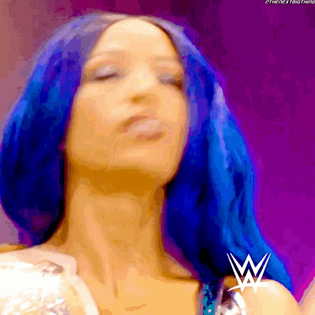 a woman with blue hair has a wrestling logo on her arm