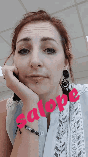 a woman wearing earrings and a bracelet with the name salope on her wrist