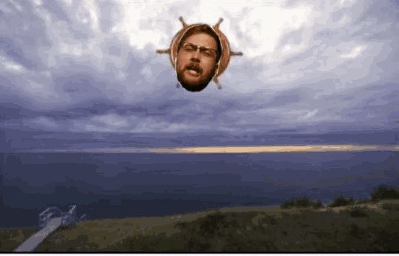 a man 's head with a steering wheel around it is floating in the air over a body of water