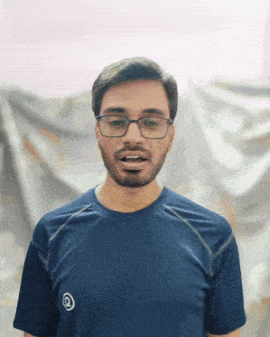 a man wearing glasses and a blue shirt with a circle on the front