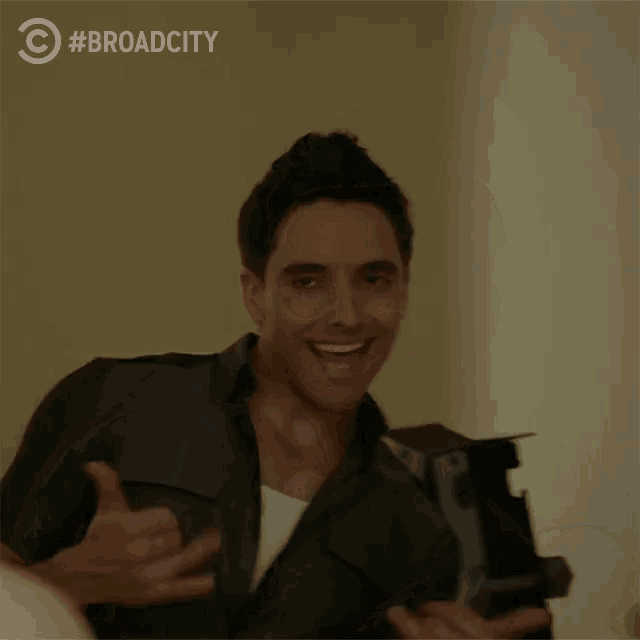a man is smiling in front of a sign that says broad city