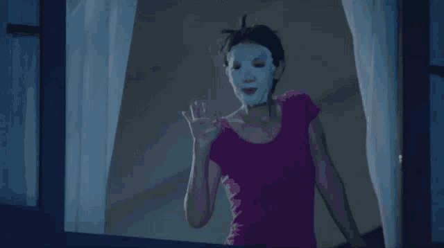 a woman with a mask on her face is looking out a window