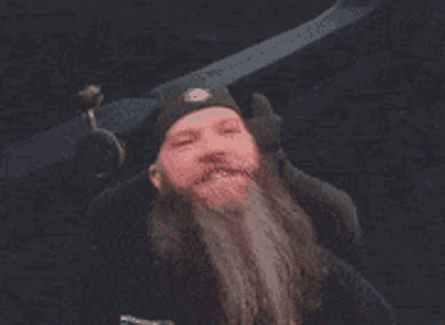 a man with a beard is wearing a black hat with the letter b on it