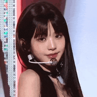 a close up of a woman wearing a microphone and a choker on a stage .