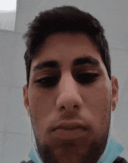 a man wearing a mask looks at the camera with his eyes closed