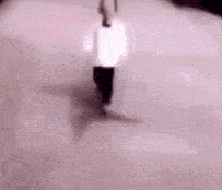a person in a white shirt and black pants is walking on a pink surface .