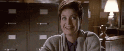 a woman is sitting at a desk in front of a filing cabinet smiling .