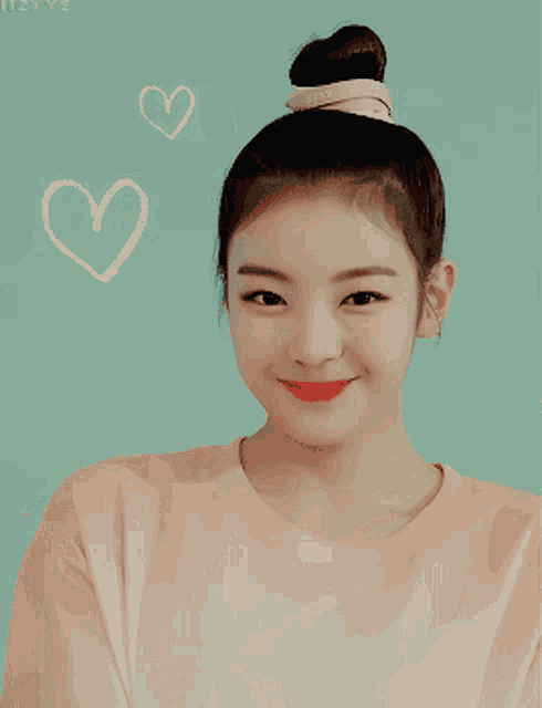 a girl with a bun on her head is smiling and making a heart shape with her hands