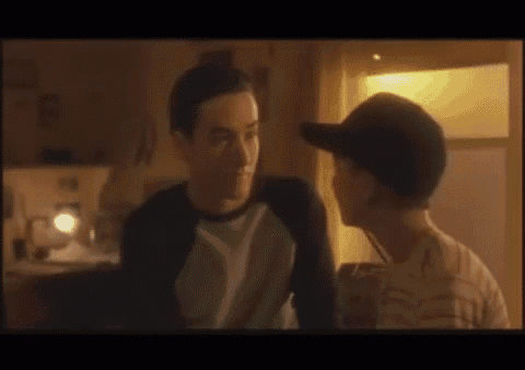 two men are looking at each other and one is wearing a hat